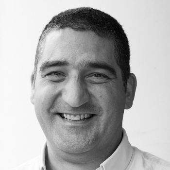 Smiling person with short hair wearing a light shirt, photographed against a plain background.